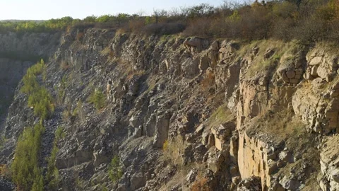 A rocky cliffside with sparse vegetation, including dry bushes Vidéo 296044733