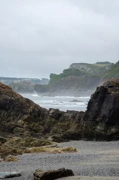 Rocky coast landscape with dramatic cliffs and waves under cloudy sky Stock Photos