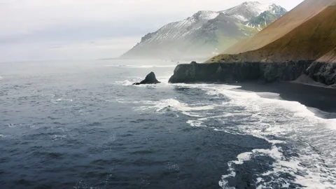 Rocky Coast washed by ocean waves. Aerial view of a black beach mossy Mountains Stock Footage 188773275