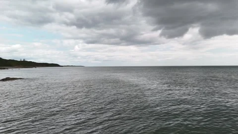 Rocky Coastal Cliffs and Waves Under Cloudy Sky 4K Stock Footage 337846952