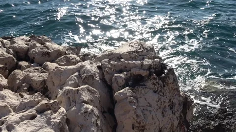 Rocky coastline against sunlit deep blue sea 動画素材 342394043