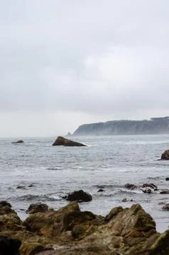 Rocky coastline and dramatic cliffs under cloudy sky, wild seascape view Stock Photos