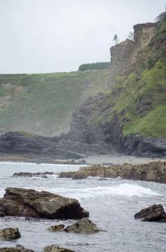 Rocky coastline with dramatic cliffs and waves on a cloudy day landscape Stock Photos