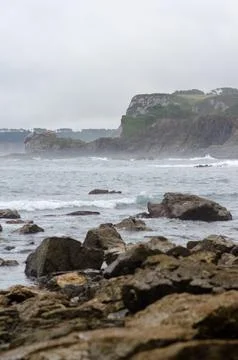 Rocky coastline with dramatic cliffs and waves on a cloudy day Stock Photos