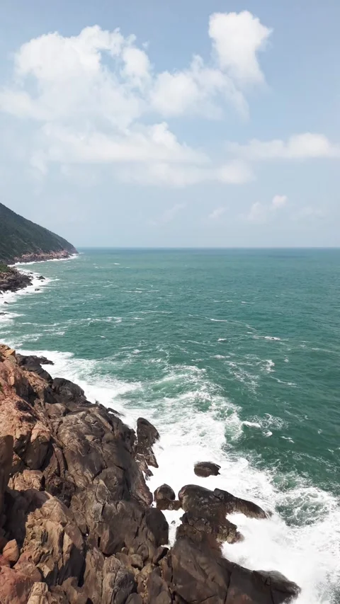 Rocky coastline with ocean waves under a blue sky 스톡 동영상 344775601