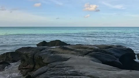 Rocky Coastline with Turquoise Ocean Waves under a Clear Blue Sky Stock Footage 337565672