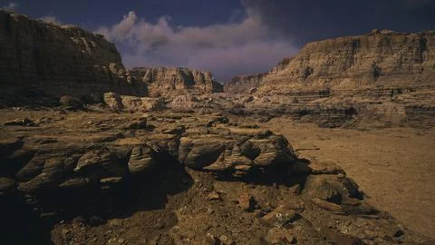 Rocky desert landscape under a dramatic sky with cloud formations at dusk Stock Illustration