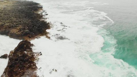 Rocky desolate ocean coast with big restless waves, aerial dolly shot Stock-Footage 107963239