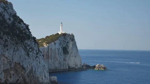 Rocky dramatic shore with light house and boat passing on the sea Video stock 115108350