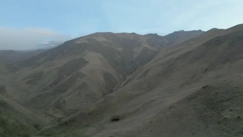 Rocky gray mountains without vegetation in haze with blue sky. Drone video. Stock Footage 253766902