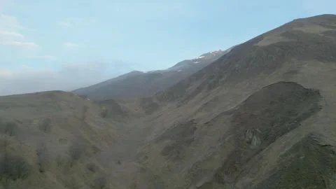 Rocky gray mountains without vegetation in haze with blue sky. Drone video. Stock Footage 253767990