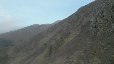 Rocky gray mountains without vegetation in haze with blue sky. Drone video. Video stock 253768283