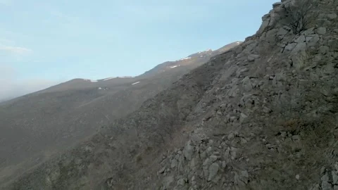 Rocky gray mountains without vegetation in haze with blue sky. Drone video. Stock Footage 253768683