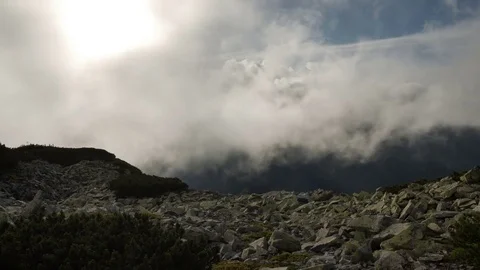 Rocky high top of the mountain with fast moving clouds. sunset after the rain Vidéo 77545928