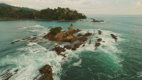 Rocky islet surrounded by breaking waves near coastal rainforest in Costa Rica Stock Footage 344914333