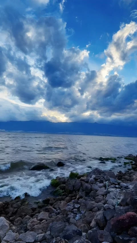 Rocky Lakeshore Under Dramatic Storm Clouds and Crashing Waves in China Видео 335984982