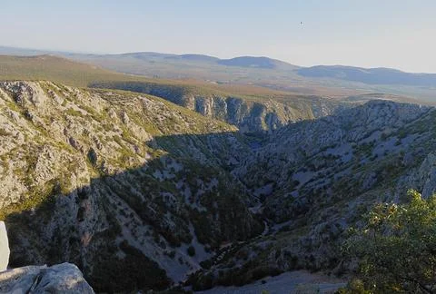 Rocky mountain gorge with limestone cliffs and distant hills. Stock Photos