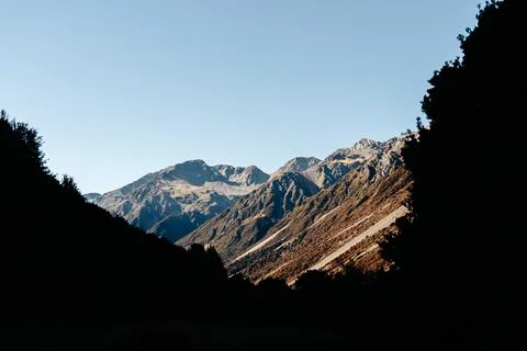 Rocky Mountain range under the clear sky with silhouetted Trees Stock Photos