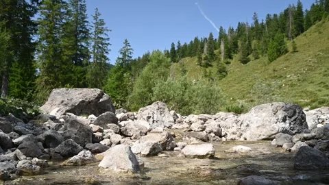 A rocky mountain stream next to a meadow in the alps in the summer Stock Footage 260844617