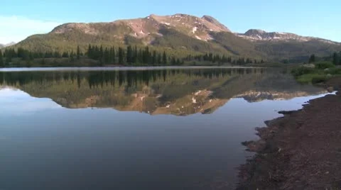 The Rocky Mountains are perfectly reflected in an alpine lake. Stock Footage