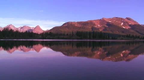 The Rocky Mountains are perfectly reflected in an alpine lake at sunset or dawn. Stock Footage