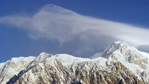 Rocky mountains covered in snow with clouds in blue sky during sunny day Stock Footage 129127196