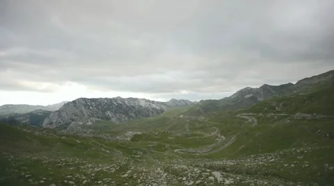 Rocky mountains pit covered with grass. Dark grey clouds passing across the sky. Stock Footage 8562050