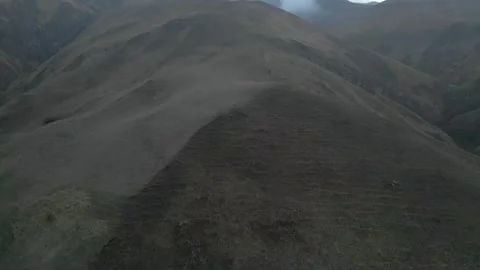 Rocky mountains without vegetation covered with clouds at dawn. Drone video. Video stock 253766514