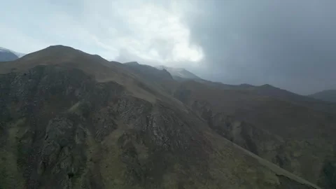 Rocky mountains without vegetation covered with clouds at dawn. Drone video. Stock Footage 253770348