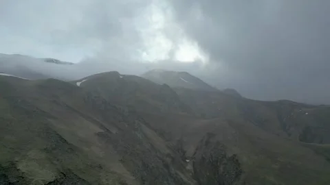 Rocky mountains without vegetation covered with clouds at dawn. Drone video. Stock Footage 253770647