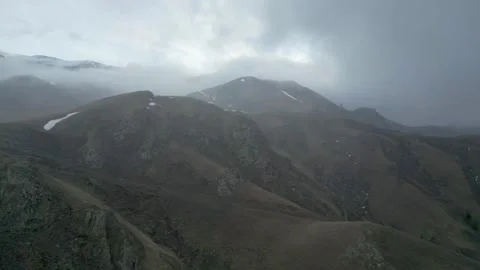 Rocky mountains without vegetation covered with clouds at dawn. Drone video. Stock Footage 253771233