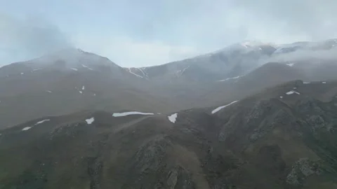 Rocky mountains without vegetation covered with clouds at dawn. Drone video. Stock Footage 253771608