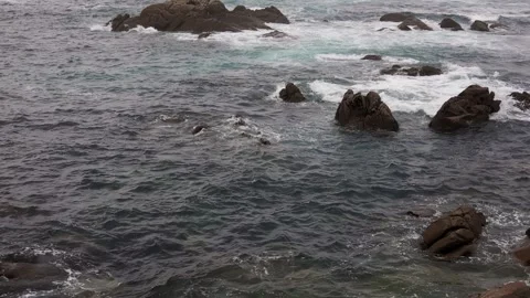 A rocky ocean shore with waves, the camera rises upwards with a view of the Video stock 242344060