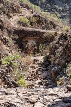 A rocky path with a bridge over a stream Stock Photos