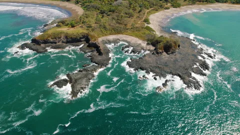 Rocky peninsula with ocean waves hitting the shore on a sunny day in Costa Rica Stock Footage 344753100