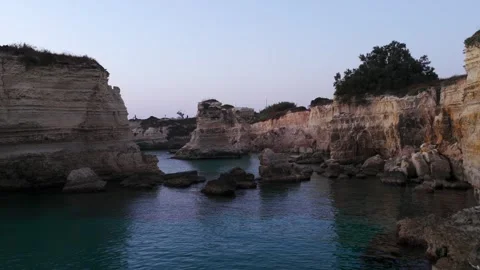 Rocky Sea Cliffs and Calm Blue Cove at Dusk. aerial push forward Stock Footage 346091715