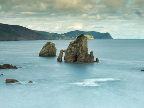 Rocky sea stack at a tranquil Basque coastline - A long exposure of a large.. Foto stock