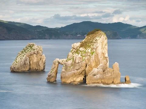 Rocky sea stack at a tranquil Basque coastline - A long exposure of a large.. Stock Photos