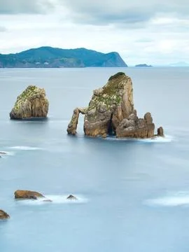 Rocky sea stack at a tranquil Basque coastline - A long exposure of a large.. Foto stock