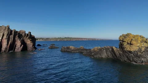 Rocky Sea Stacks and Cliffs Above Calm Ocean Water Stock Footage 333414608