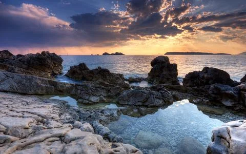 Rocky Seascape at Sunset with Dramatic Clouds and Tide Pools Stock Photos