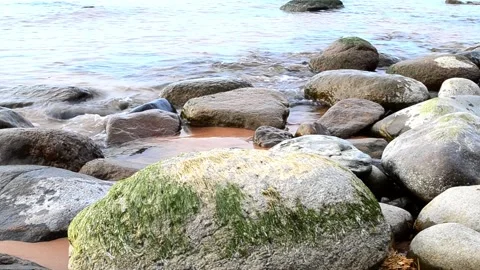 Rocky seashore. Large and small boulders on the beach. Waves roll over sea. Stock Footage 153010327