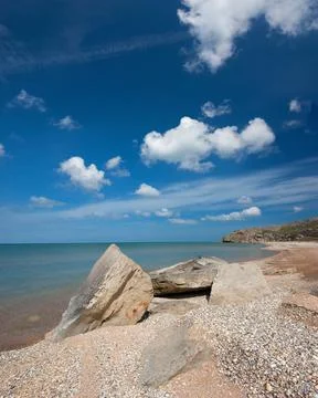 Rocky Seashore with Shell Beach and Dramatic Blue Sky Stock Photos