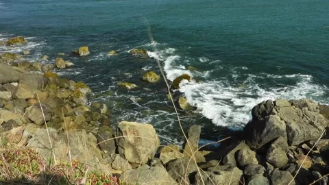 Rocky seaside view from a small cliff overlooking the ocean waves splashing Stock-Footage 161518217