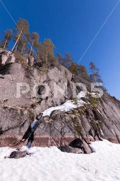Rocky shore at a frozen lake Stock Photos