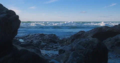 Rocky shore at low tide as waves crash in background, parallax slider Stock Footage 149659896