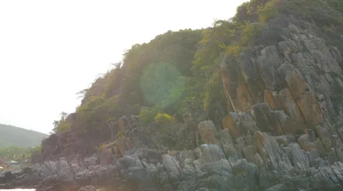 Rocky shore with trees in rays of sun. Panoramic view from moving boat 库存影片 62619865