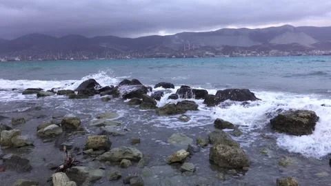 Rocky shoreline with storm waves in the foreground and a distant commercial.. Stock Footage 339967433