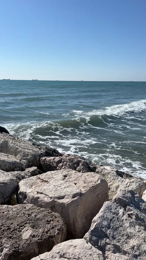 Rocky Shoreline with Waves and Distant Ships Stock Footage 310939408