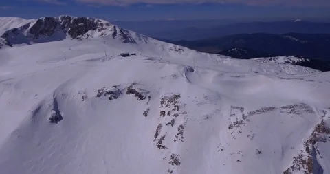 Rocky steep north faces in snow and top of ski center reveal Stock Footage 93481978